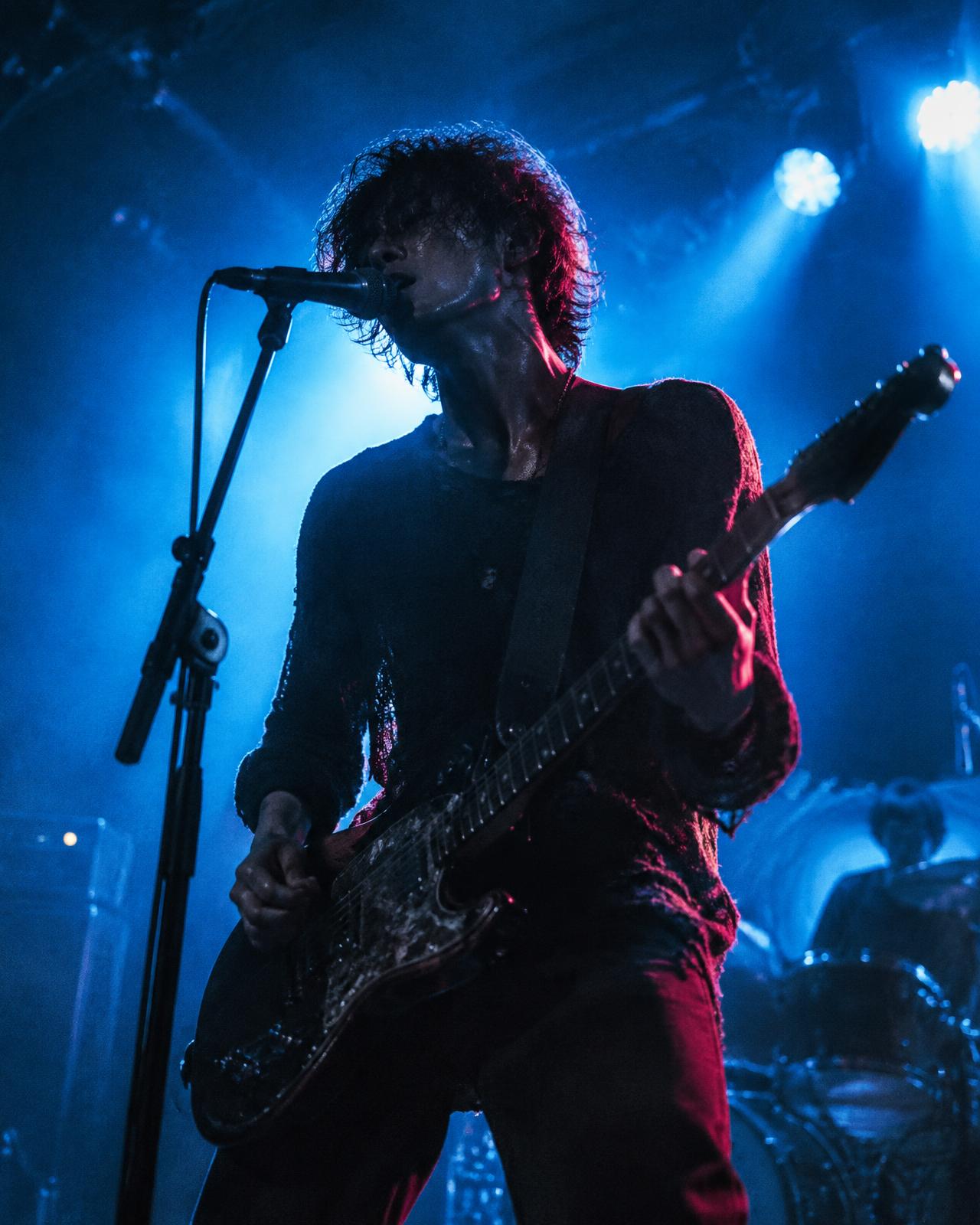 Artist playing guitar under electric blue stage lights